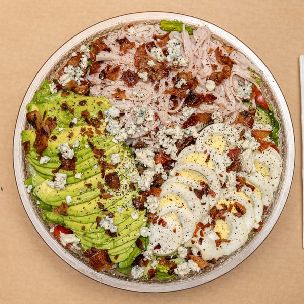 Overhead view of a large Appletree Deli salad with turkey, avocado, hard-boiled eggs, bacon, and blue cheese.